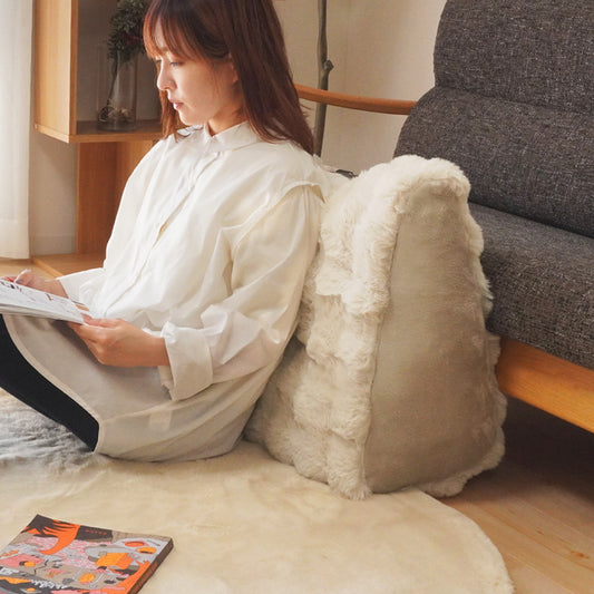 あったかいファー素材のもこもこ背もたれリラックスクッションに持たれている人