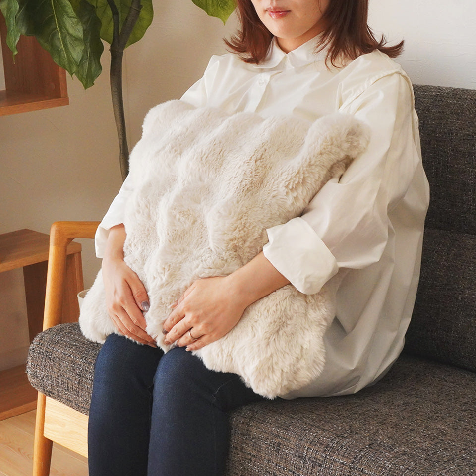 あったかいファー素材のもこもこクッションカバーを膝に置いたイメージ
